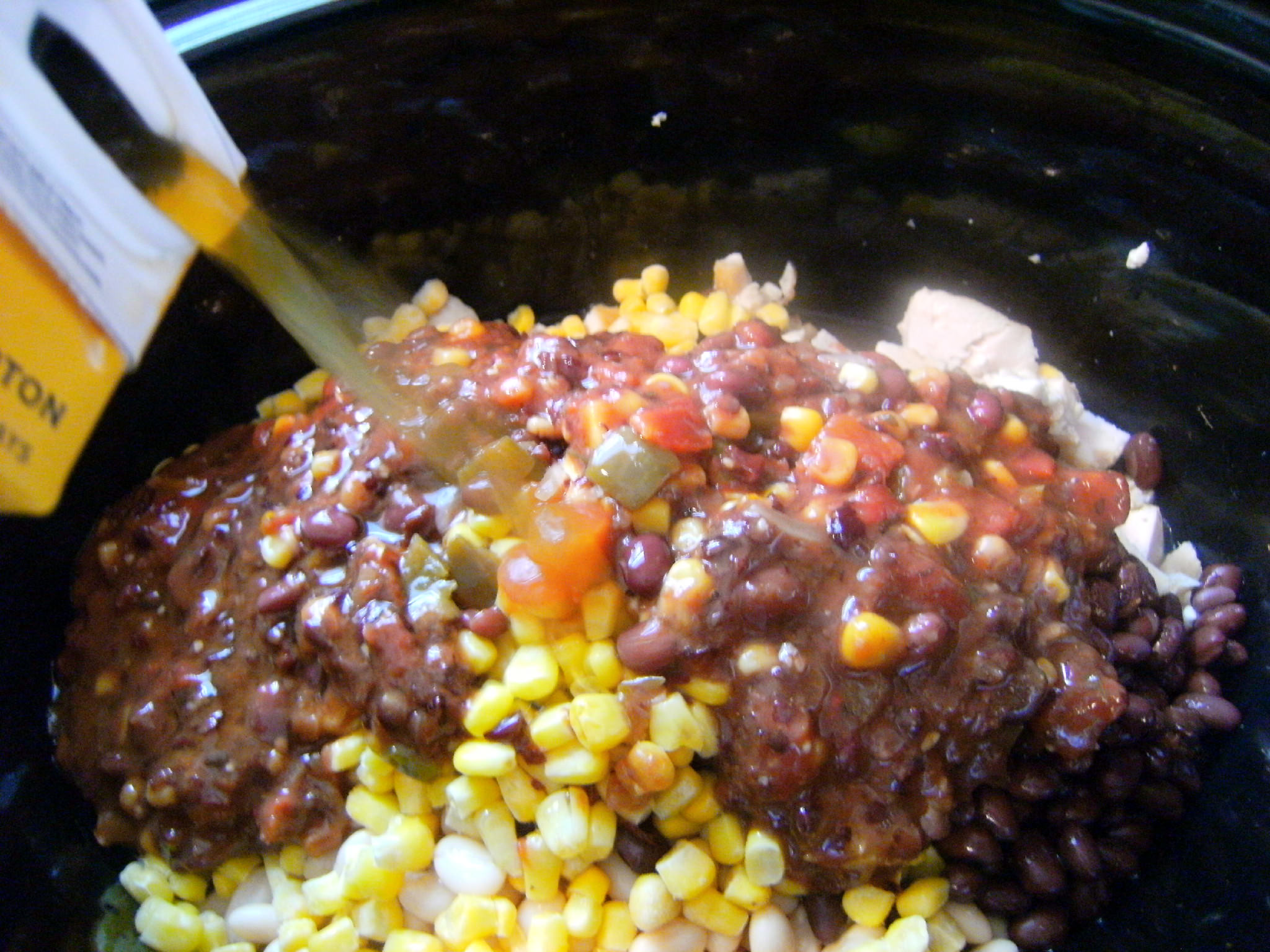 adding ingredients needed to make slow cooker chicken chili